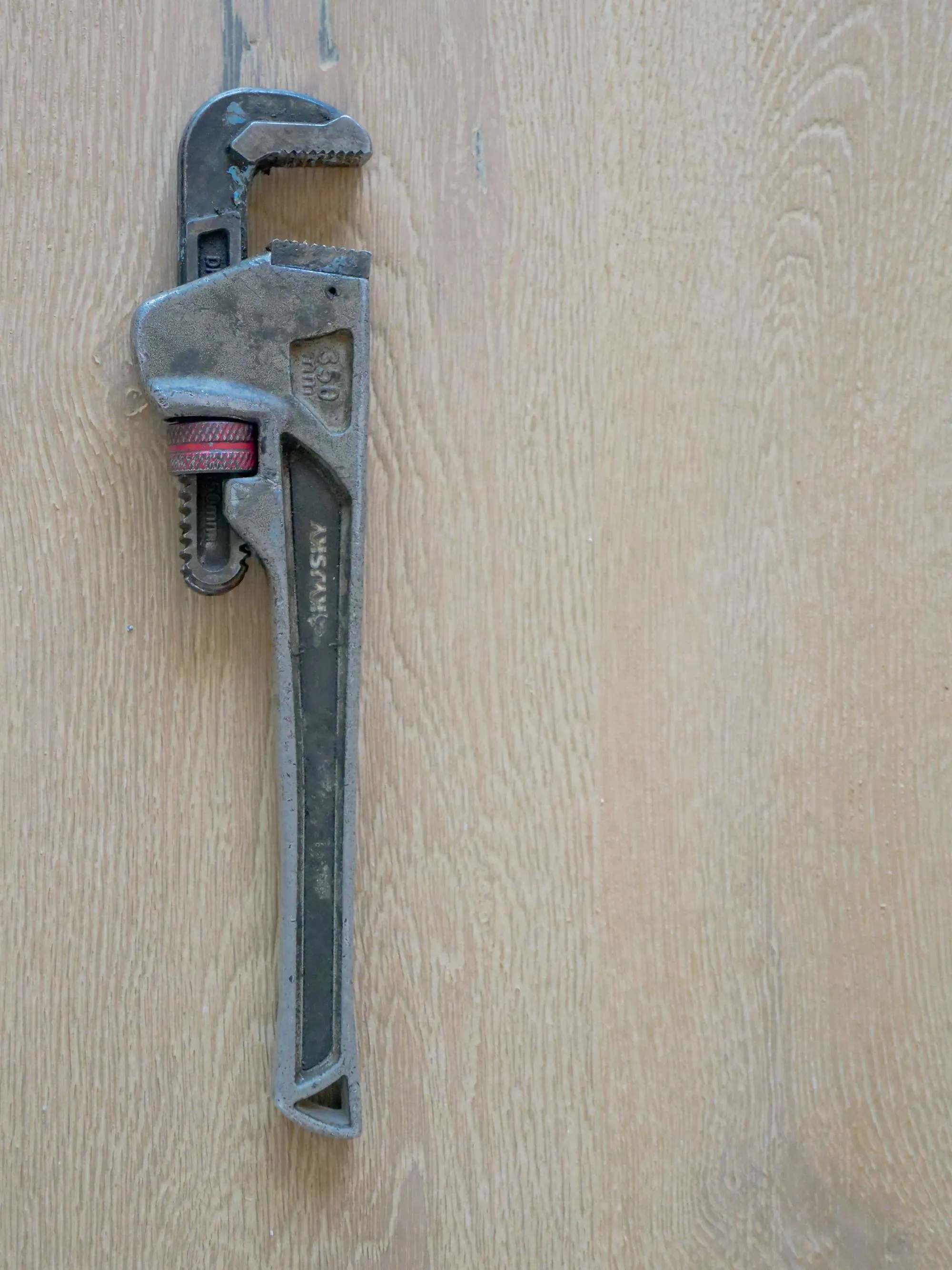 A pipe wrench resting on a workshop bench
